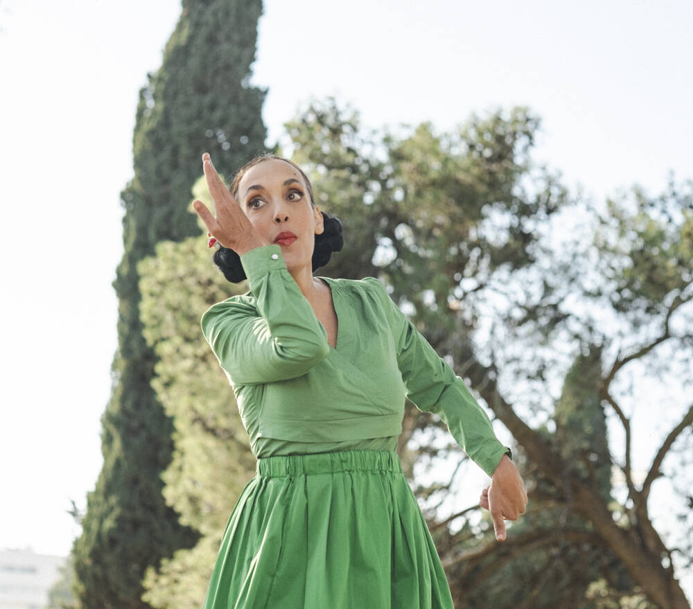אמנית הקול ויקטוריה חנה לבושה ירוק רוקדת בשדה הפתוח